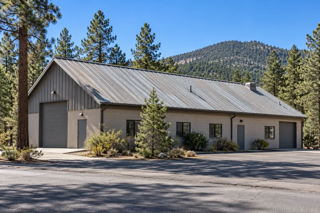 Commercial shop building with a steep standing-seam metal roof among ponderosa pines in Doney Park, AZ